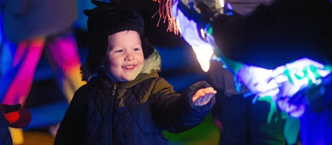 Close up shot of a young boy in winter clothing at night.