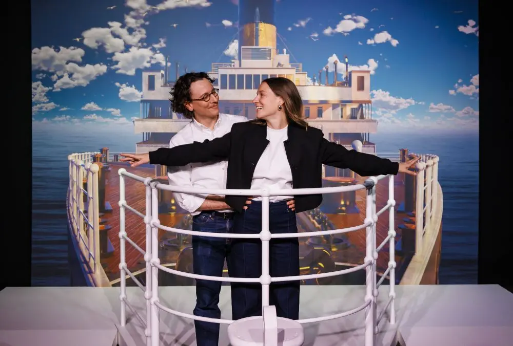 A couple standing on a recreation of the Titanic's deck at the Legend of the Titanic Exhibition