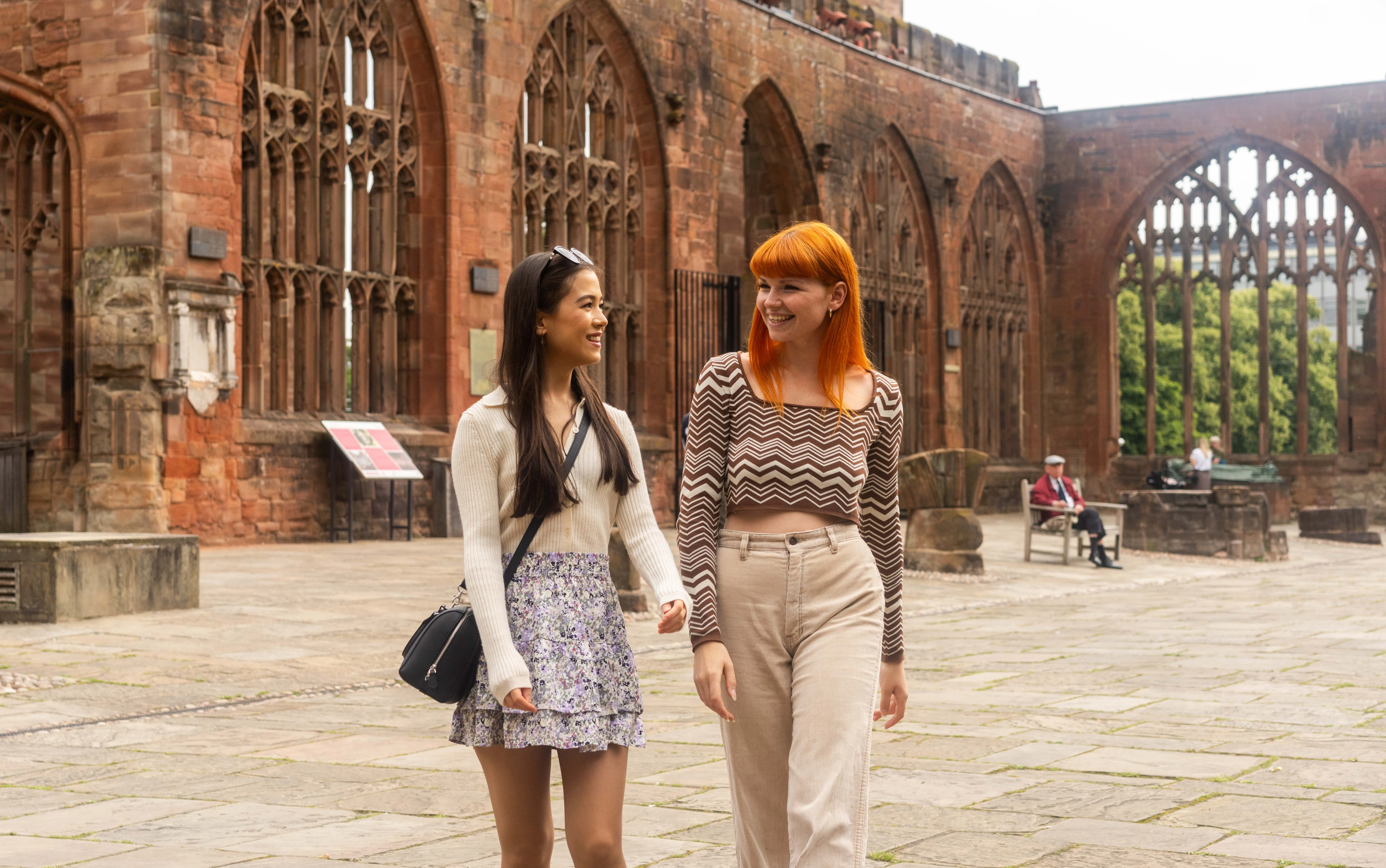 Two friends walking with Coventry Cathedral in the background.
