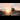 Jobs in Rail: Railway worker in a hard hat and high-visibility vest inspecting train tracks at sunset.