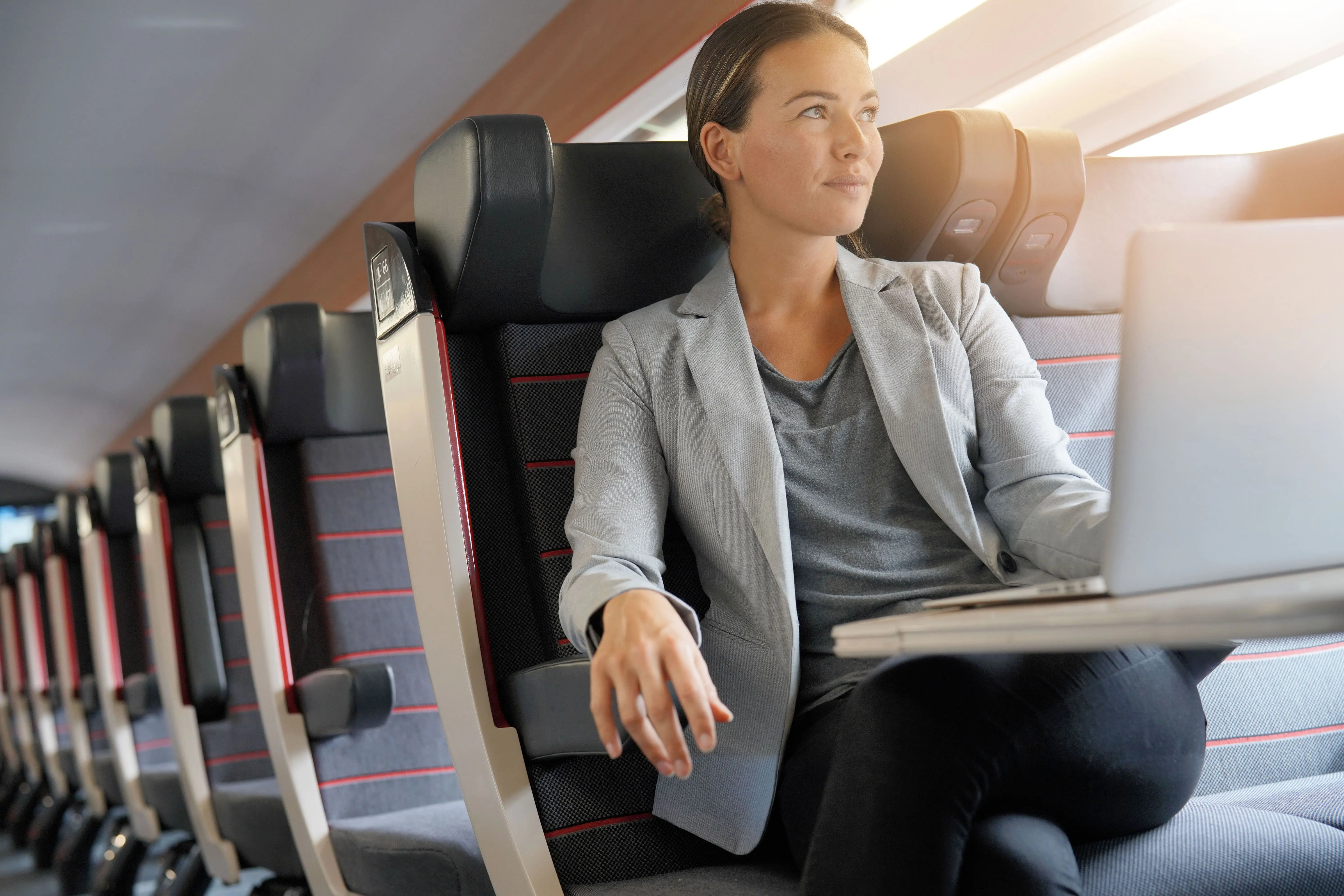 First Class Train Tickets: A woman works on a laptop whilst relaxing in a First Class train seat.