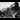 A black and white image of a train sat amongst a pile of rubble and destroyed railway track