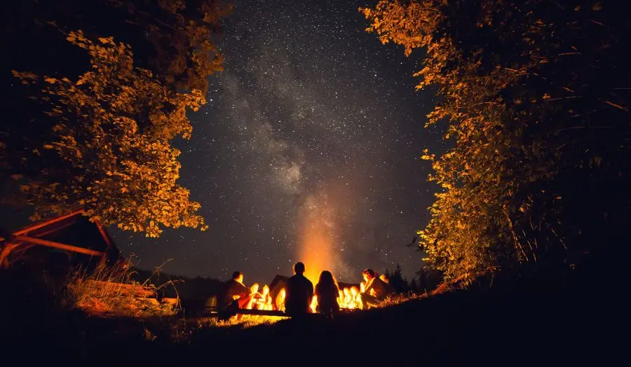 View from behind of people sat around a large fire.