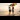 Lesbian couple walking in the sea holding a Pride flag.