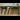 Row of books standing on a wooden bookshelf outdoors.