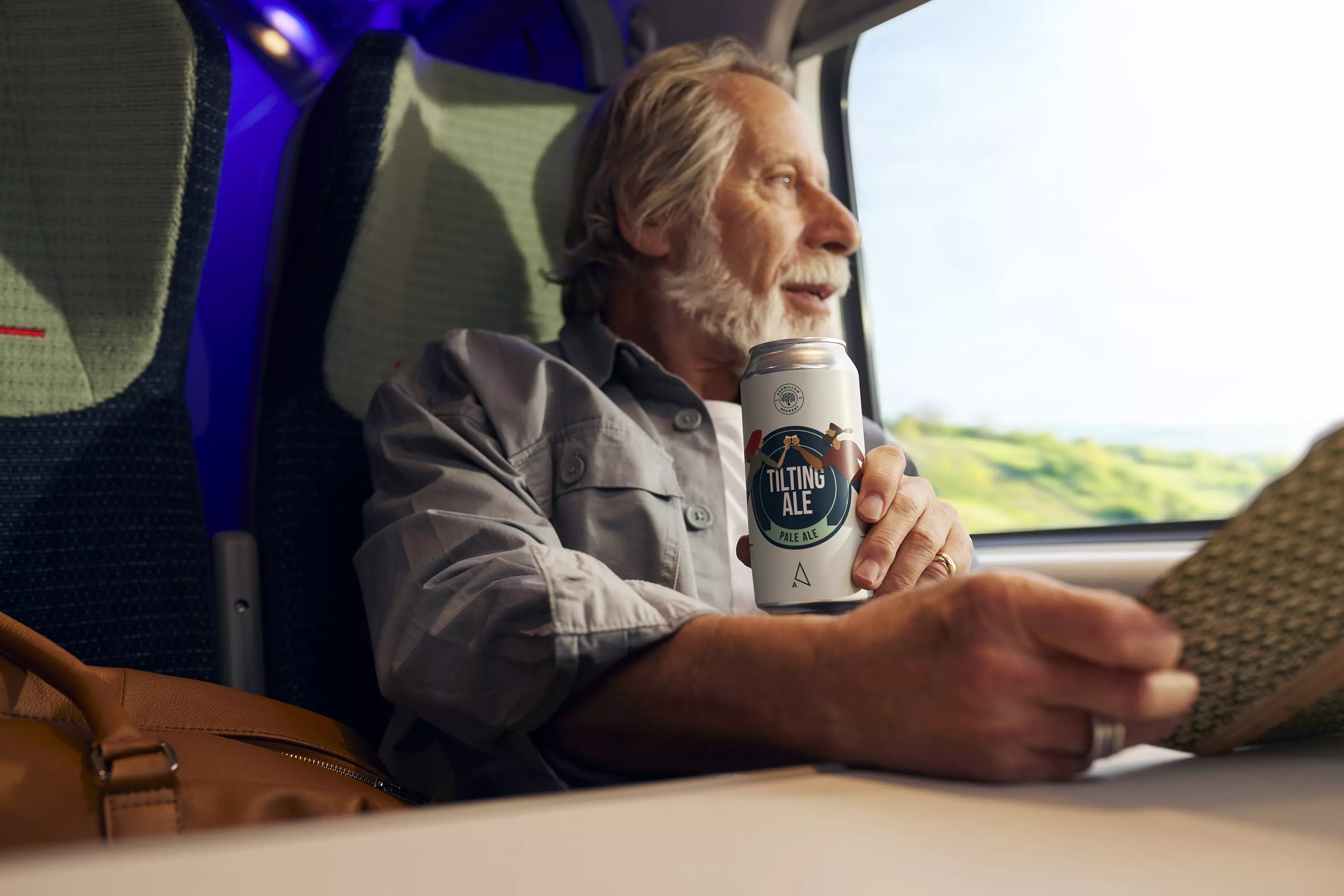 A person sitting in a train holding a can