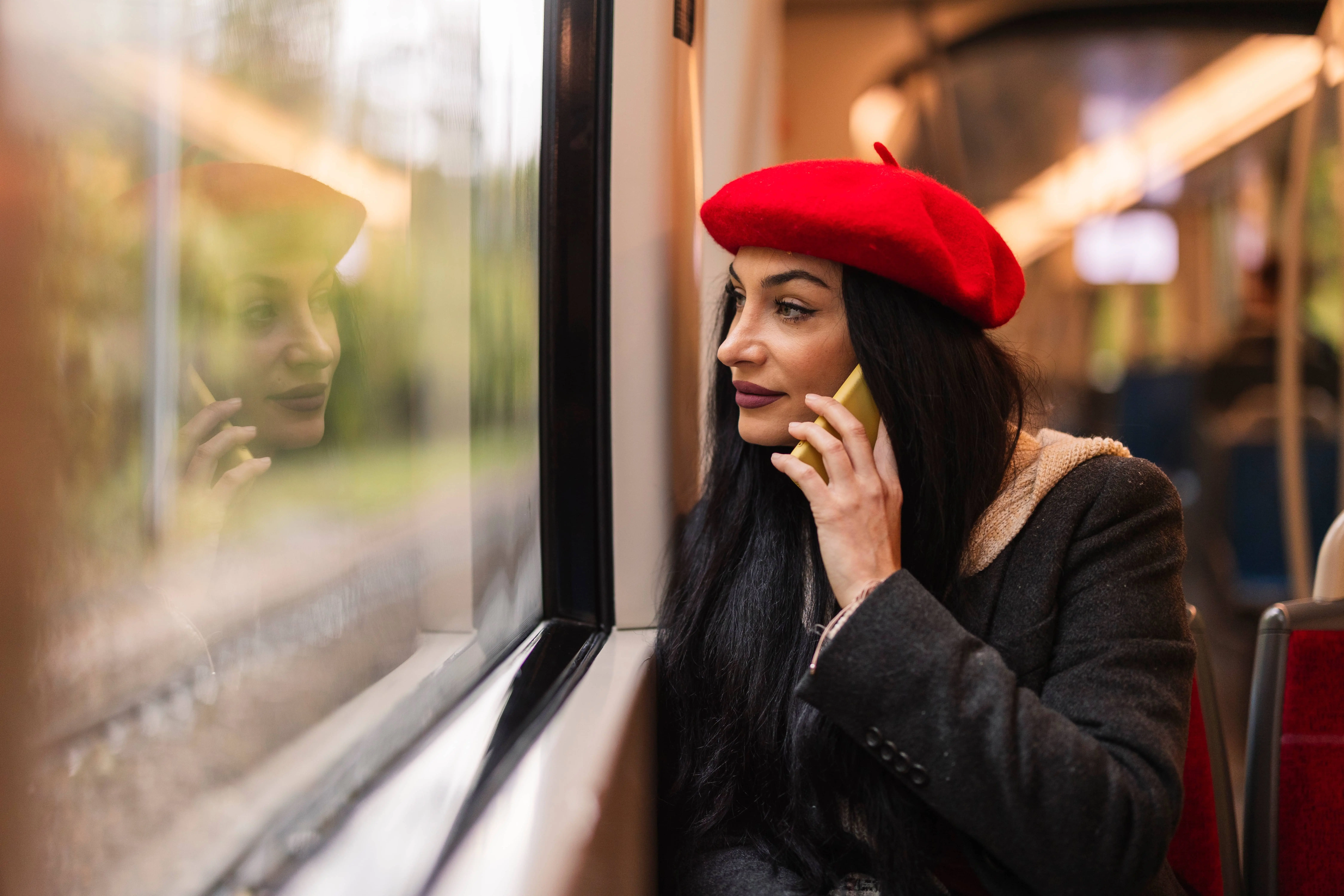 Train Idioms: A woman in a red beret speaking into a phone on a train