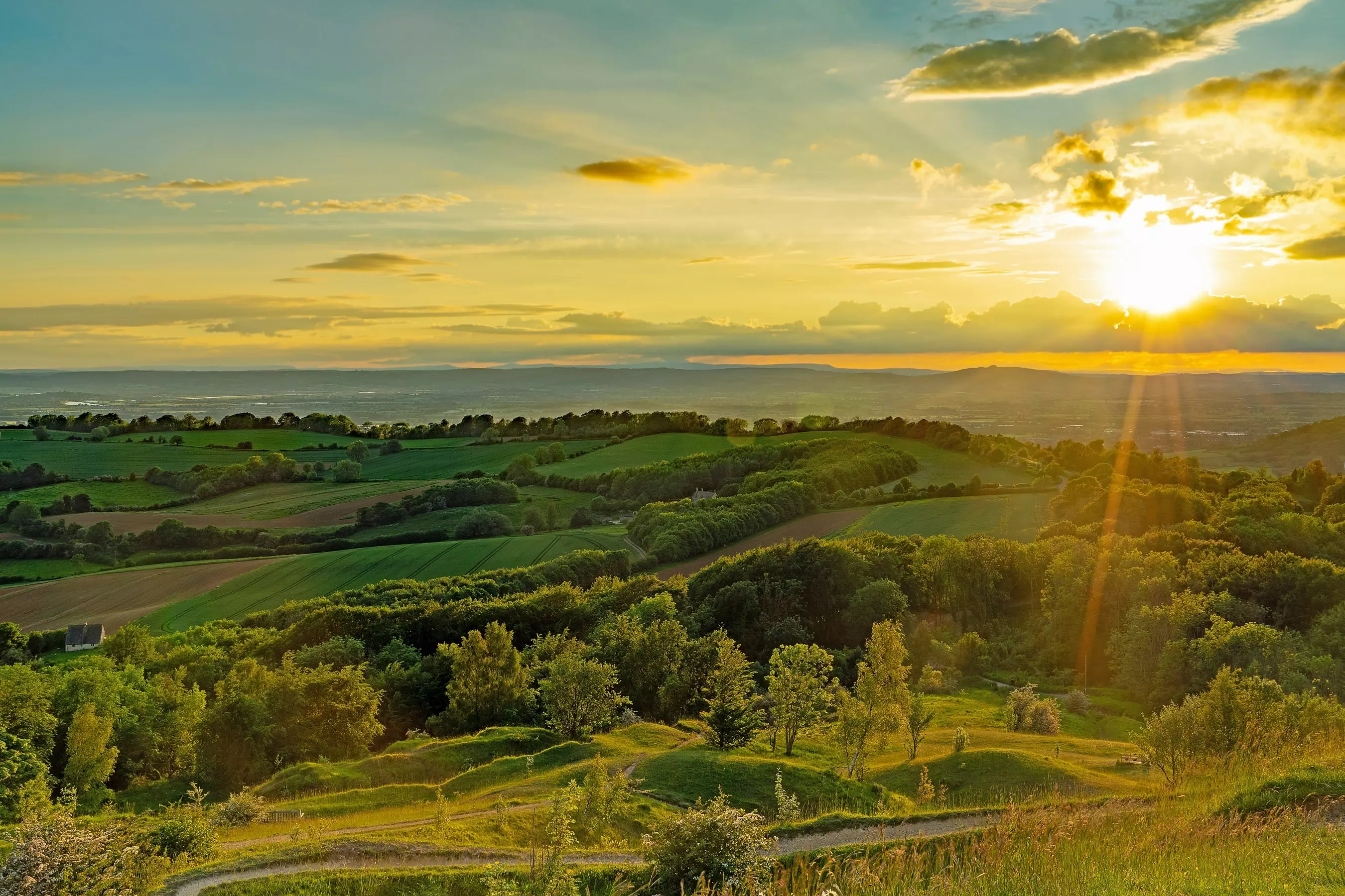 A landscape view of the Cotswold countryside at sunset.