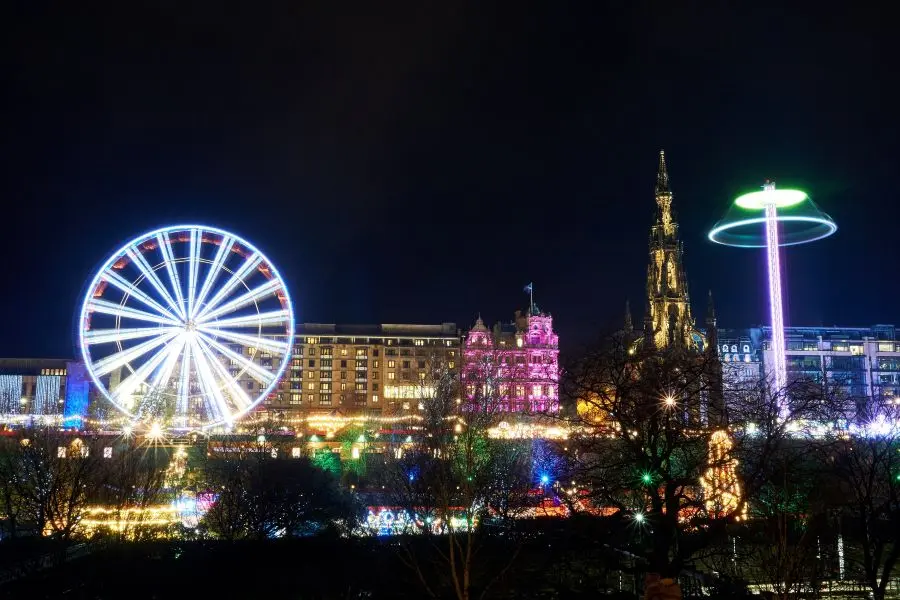 Christmas market in Princess Street Gardens with Fair Ground Ride, Scott Monument and russian wheel during Christmas, Boxing day and New Year at Edinburgh, Scotland.