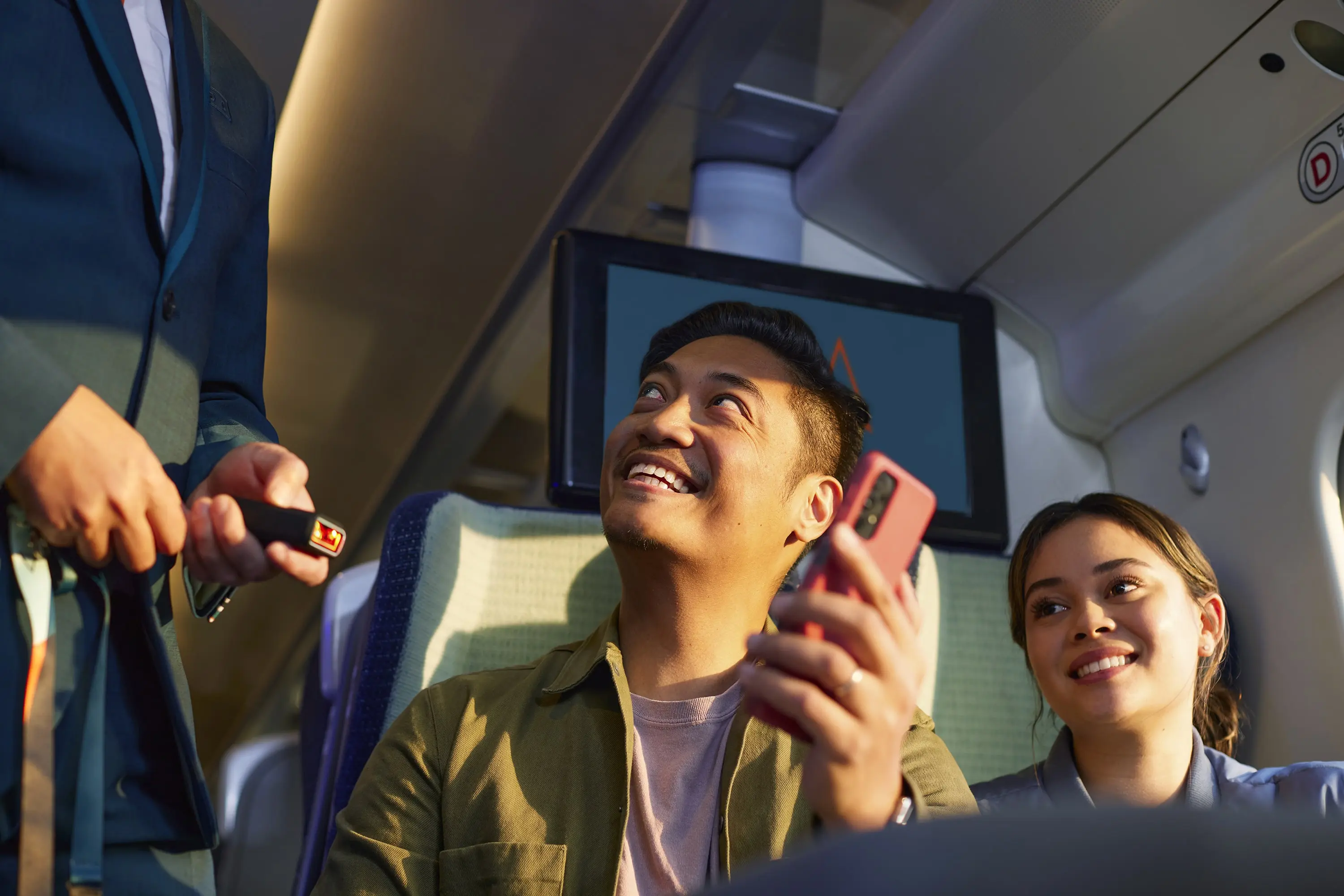 Man sat on an Avanti train having his e-ticket scanned, with a woman sat beside him